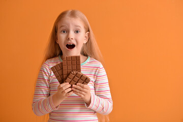Surprised little girl with chocolate on color background