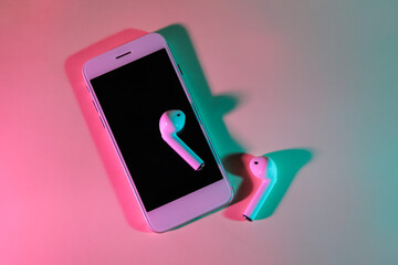 Modern mobile phone and earphones on color background