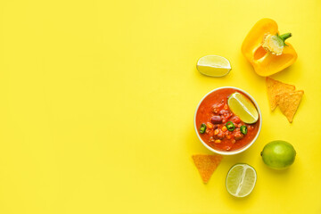 Bowl with tasty chili con carne, nachos and ingredients on color background