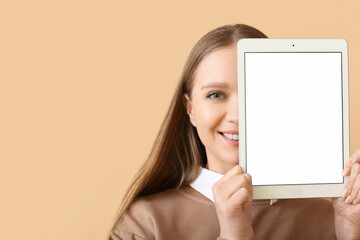 Beautiful young woman holding tablet computer with blank screen on color background