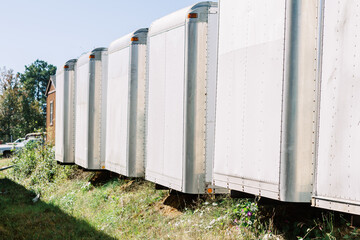 Horizontal image of many white empty trailers lined up outside at an outdoor junk salvage yard to...