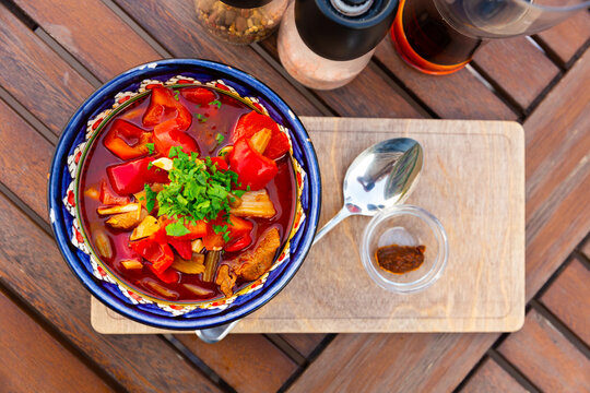Uyghur laghman served in soup bowl with spoon and sauce.
