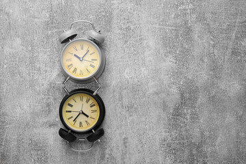 Two old style alarm clocks on textured grey background