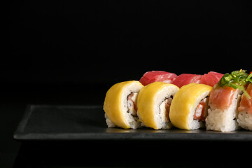 Tray with tasty sushi rolls on dark background, closeup