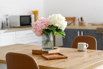 Vase with hydrangea flowers on table in kitchen