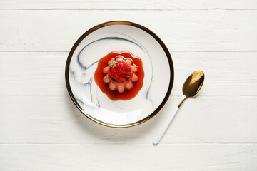 Delicious panna cotta with strawberry in plate on light wooden background