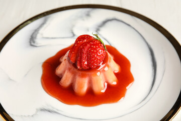 Delicious panna cotta with strawberry in plate on table, closeup