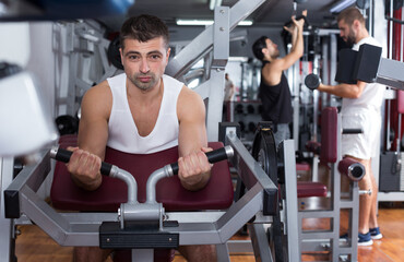 Portrait of athletic man during workout with power exercise machine in gym club