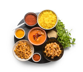 Board with traditional Indian food and spices on white background