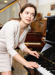 Fototapeta na wymiar Young woman buys a piano in a music store. High quality photo