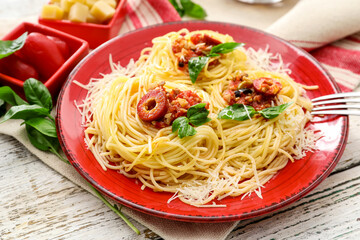 Plate of tasty Pasta Alla Puttanesca on white wooden background