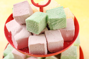 Dessert stand with tasty sweet marshmallows on color background