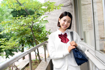 スクールバッグを持った屋外の笑顔の女子学生