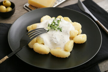 Plate of delicious gnocchi with creamy sauce on table
