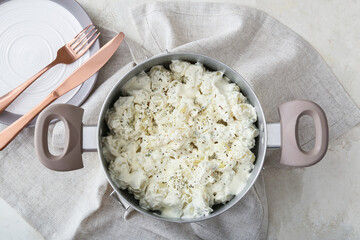 Cooking pot of delicious gnocchi with creamy sauce on light background
