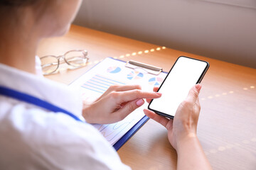 Woman using mobile phone at table in office, closeup