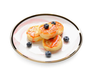 Plate with cottage cheese pancakes and blueberries on white background
