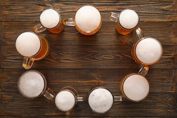Frame made of mugs with cold beer on wooden background