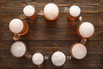 Frame made of mugs with cold beer on wooden background