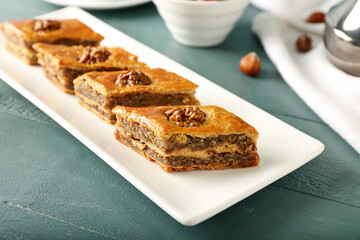 Plate with tasty baklava on blue wooden background, closeup