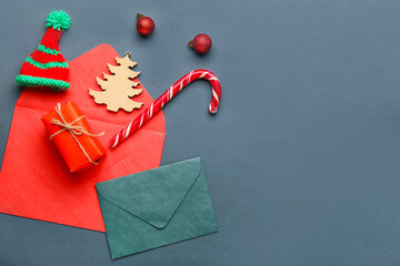 Envelopes with Christmas decor and candy cane on dark background
