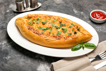Plate with tasty Turkish Pizza on black background
