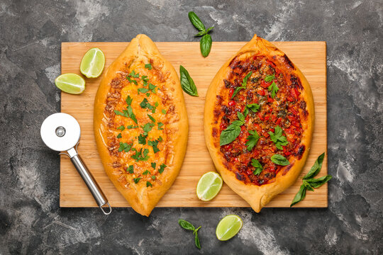Wooden board with tasty Turkish Pizza on black background