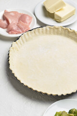 Raw dough and ingredients for preparing pot pie on light background