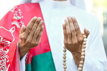 Praying Muslim man with flag of Afghanistan and tasbih, closeup
