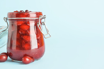 Jar of delicious dogwood jam on blue background