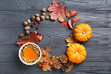 Frame made of autumn composition with pumpkins, pie and nutmegs on dark wooden background