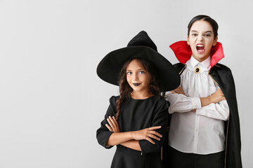 Cute little children in Halloween costumes on light background