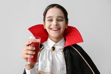 Cute little boy dressed as vampire for Halloween on light background