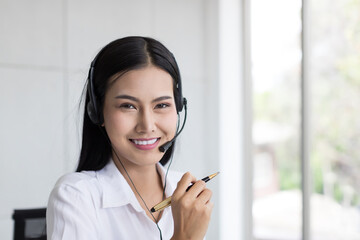 Asian call center female worker at work. Smiling female customer support operator with headset...