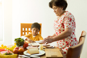 little boy with his grandmother, making a sandwich in the kitchen