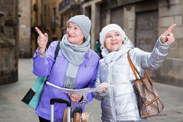 Fototapeta premium Senior woman with female friend traveling together looking for destination with city map.