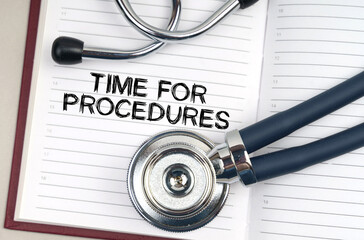 On the table is a stethoscope, a pen and a notebook in which it is written - Time for procedures