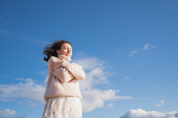 A romantic girl in a warm sweater hugs herself. The brunette dreamily closed her eyes. A woman...