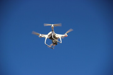 Quadcopter flying in the blue morning sky. Drone in the air.