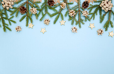 Green Christmas tree branches with New year's toys. Cones, bows and Gold stars on a sky-blue...