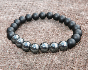 mineral bracelet, bracelet jewelry made of different types of round gemstone beads on a wooden background.  onyx, hematite