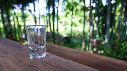 Small clear glass placed on a beautiful natural wooden plate.