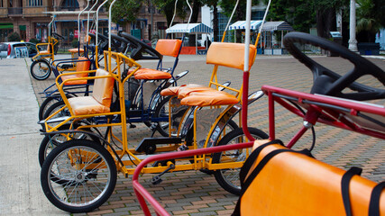 Fototapeta na wymiar Empty orange cycle rickshaws stand on the street of the resort town near the and await tourists.
