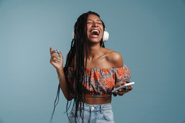 Young black woman singing while listening music with headphones