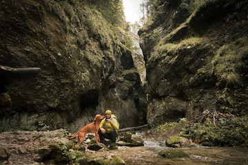 Traveler Man trekker with him dog walk around mountains in sunny day. Backpacker walking in Outdoors. Health care, authenticity, sense of balance and calmness.