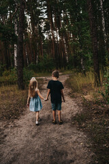 Fototapeta premium girl and boy holding hands in the forest