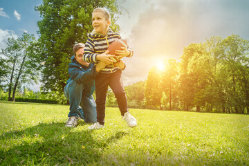 Fototapeta premium Father and son playing football, Father's day, Playful Man teaching Boy rugby outdoors in sunny day at public park. Family sports weekend.