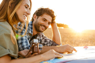 White couple smiling while examining map during travel on car