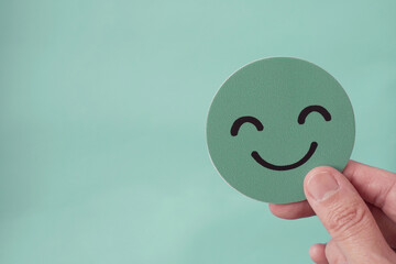 Hands holding green happy smile face paper cut, good feedback rating,positive customer review,...