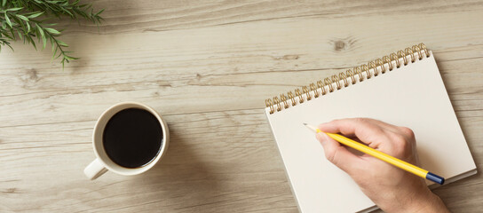 The man who is writing notes in the notebook on a table....